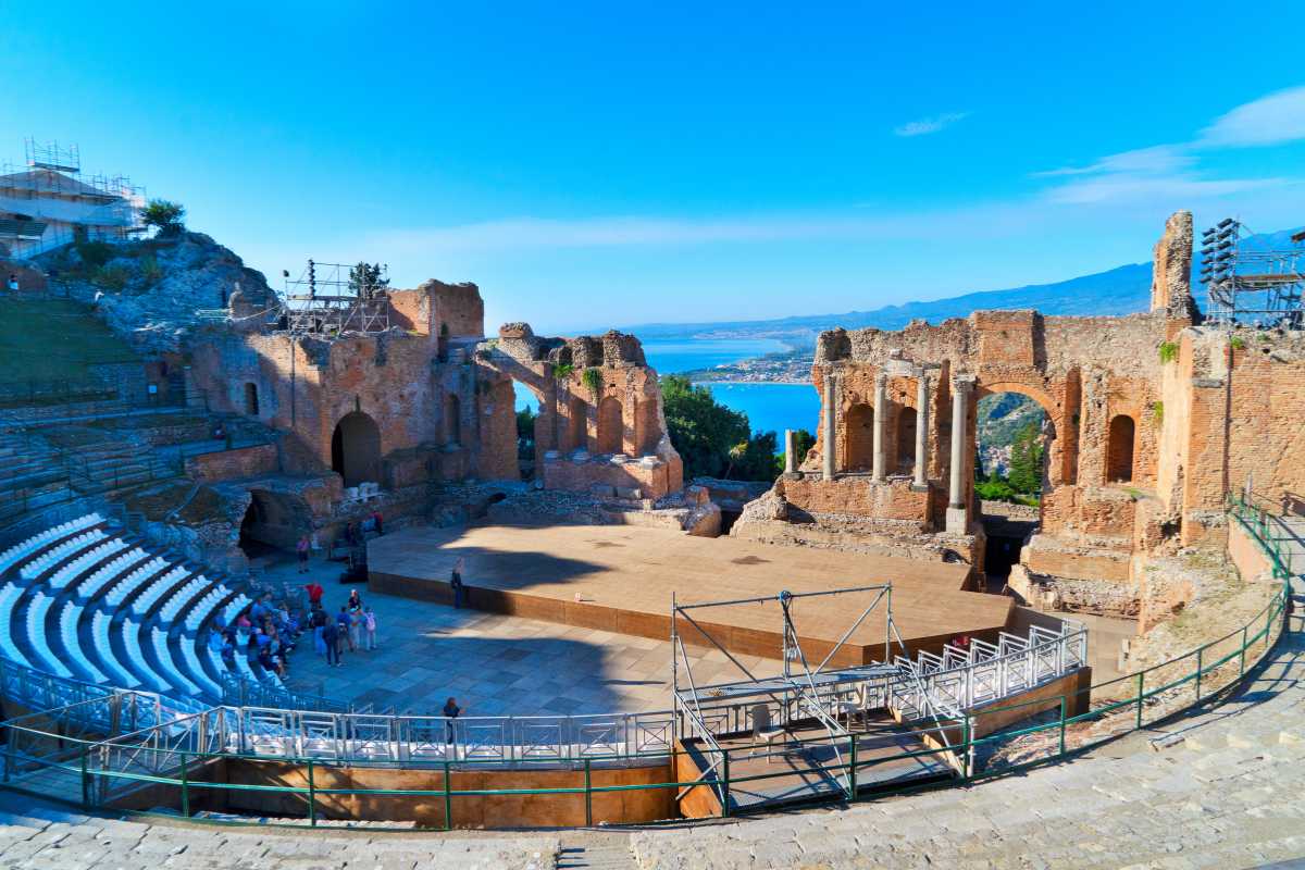 Escursione sull’Etna con paesaggio lavico, gruppo di turisti che cammina sul cratere, vista panoramica sulla costa e Taormina in lontananza