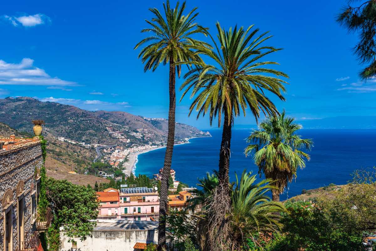 Scorcio di una trattoria tipica siciliana nel centro storico di Taormina, atmosfera serale e tavoli all’aperto