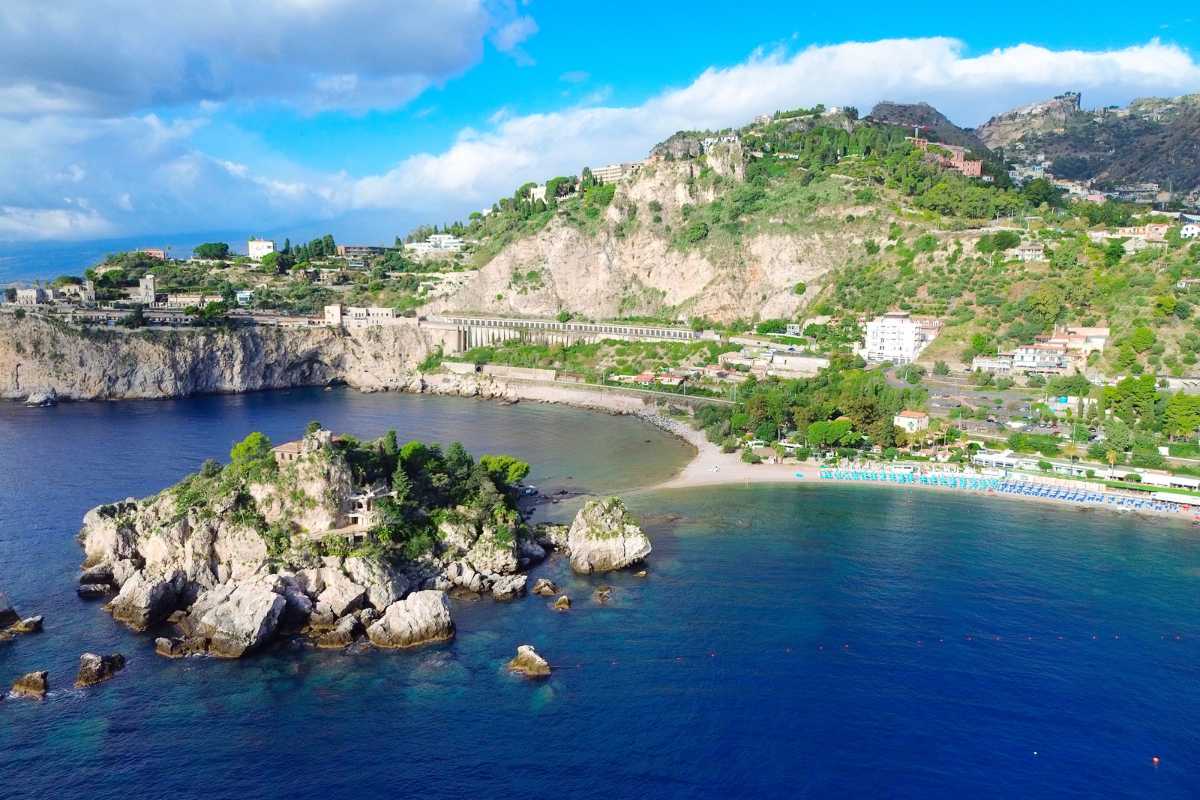 Persone che fanno snorkeling nelle acque limpide di Isola Bella, scogli e vegetazione, atmosfera estiva a Taormina
