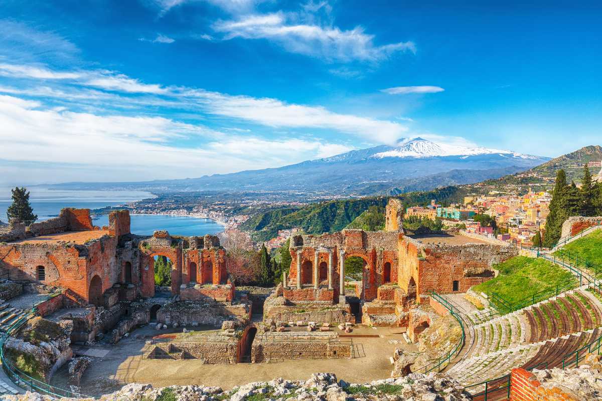 Interno di una camera familiare in un hotel di Taormina: letti singoli per bambini, lettino da viaggio, colori chiari, atmosfera accogliente, dettagli per bambini (peluche o giochi in vista)